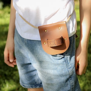 Child wearing a brown leather sword sheath with rope belt, shown on the waist during outdoor play