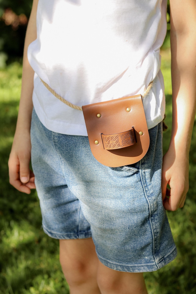 Child wearing a brown leather sword sheath with rope belt, shown on the waist during outdoor play