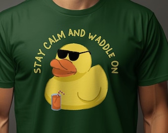 May include: A green t-shirt featuring a yellow rubber duck wearing sunglasses and holding a drink. The text on the shirt reads "Stay Calm and Waddle On."