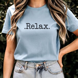 May include: A light blue t-shirt with a black graphic that says ".Relax."