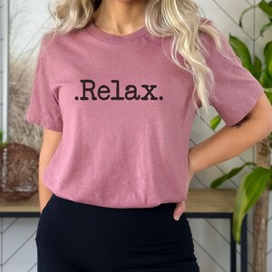 May include: A mauve short-sleeved t-shirt with the text ".Relax." printed in black.