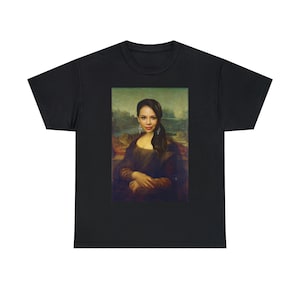 Puede incluir: Una camiseta negra con una imagen impresa de una mujer en una pintura, similar a la Mona Lisa, con un fondo de paisaje.