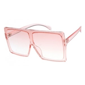 Puede incluir: Gafas de sol cuadradas de color rosa con lentes degradados. Las gafas tienen un marco transparente.