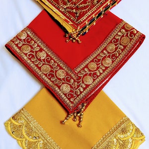 Könnte beinhalten: Drei quadratische Schals mit goldener und roter Stickerei. Der obere Schal ist gelb mit einem roten und goldenen Rand. Der mittlere Schal ist rot mit einem goldenen Rand. Der untere Schal ist gelb mit einem goldenen Rand.