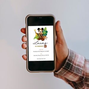 May include: A smartphone screen displaying a birthday invitation for Lucas turning 3. The invitation features a cartoon image of Mickey Mouse dressed as an explorer with a giraffe and monkey. The invitation includes the date, time, and location of the party.
