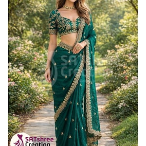 May include: A teal green sari with gold embroidery. The sari features a matching blouse with short sleeves and intricate gold detailing. The border and edges of the sari are also adorned with gold embroidery. The image includes the logo for SATshree Creation.