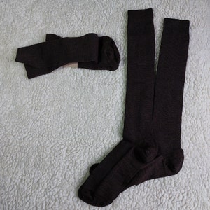 May include: A pair of brown knee-high socks. The socks are folded and laid out on a white fluffy surface.
