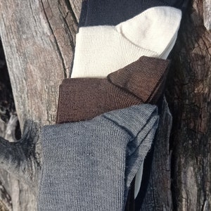 May include: Four pairs of socks stacked on top of each other. The socks are in different colors: gray, brown, white, and black.