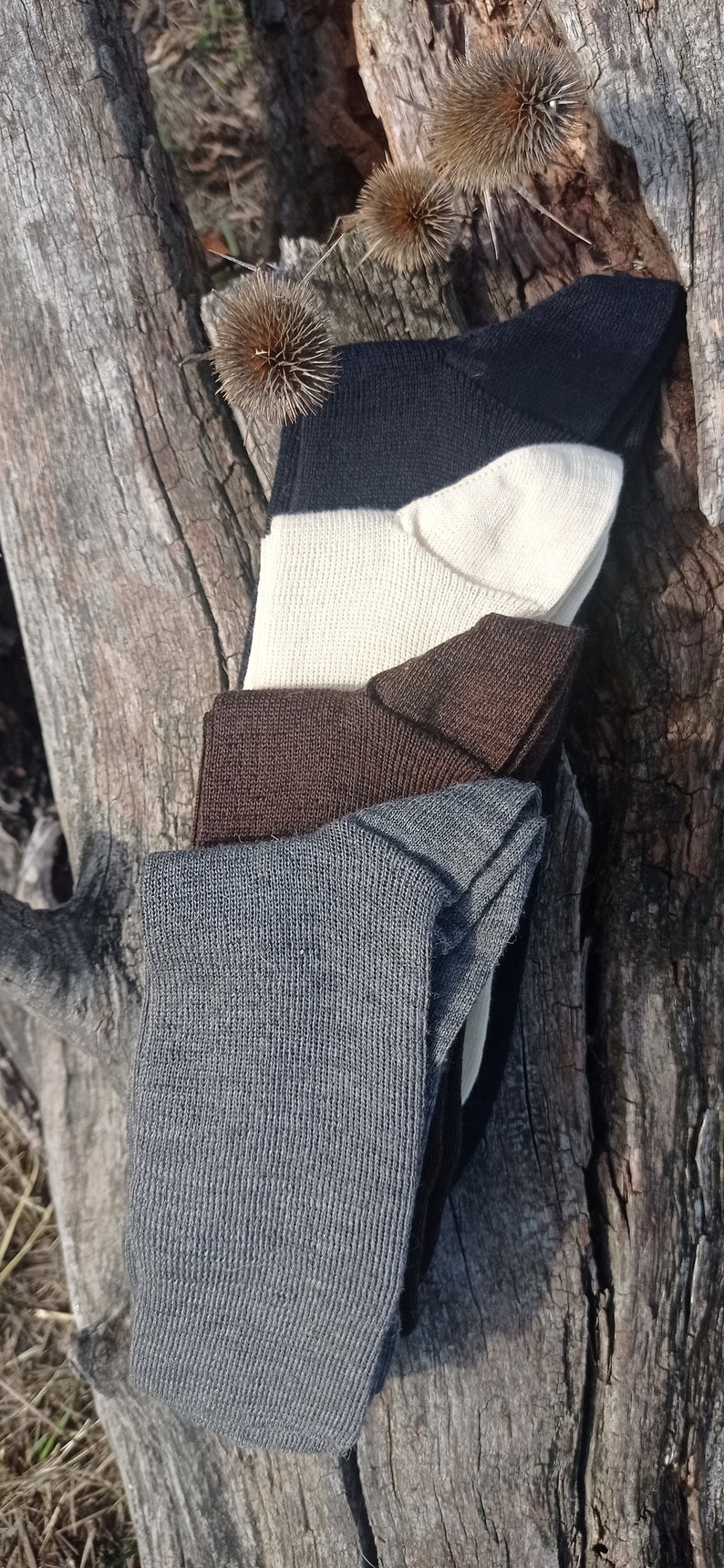 May include: Four pairs of socks stacked on top of each other. The socks are in different colors: gray, brown, white, and black.