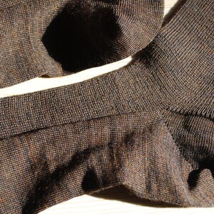 May include: A pair of brown socks made of a soft, textured fabric. The socks are folded in half and show the ribbed texture of the fabric.