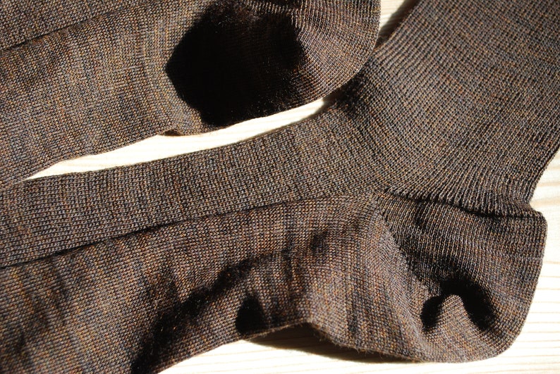 May include: A pair of brown socks made of a soft, textured fabric. The socks are folded in half and show the ribbed texture of the fabric.