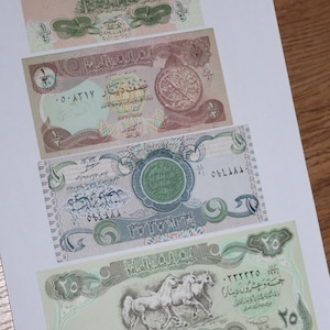 Puede incluir: Se muestran cuatro billetes iraquíes de diferentes denominaciones. Los billetes presentan escritura árabe e imágenes, incluyendo palmeras, un emblema circular y caballos. Los billetes son en tonos verdes, rosas y marrones.
