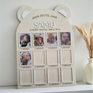 Può includere: Una cornice portafoto in legno per bambini a forma di testa di orso. Ha spazi per foto da 1 a 12 mesi. La cornice include il nome "SAMU" e la data, l'ora, il peso e l'altezza del bambino. L'altezza del bambino è di 56 cm.