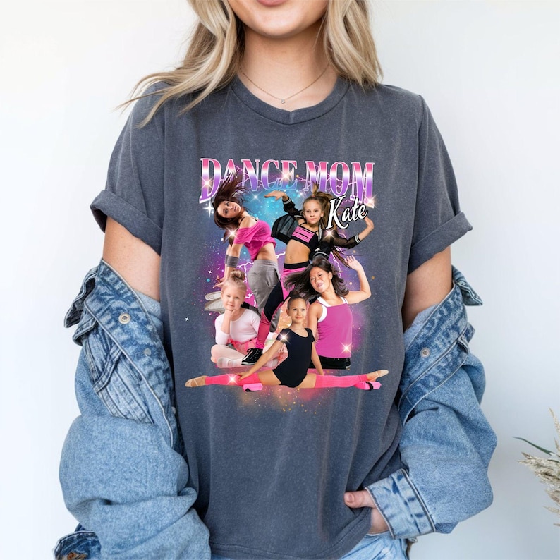 K&ouml;nnte beinhalten: Ein dunkelgraues T-Shirt mit einem grafischen Aufdruck einer Gruppe tanzender M&auml;dchen. Der Text "Dance Mom Kate" ist auf dem Shirt aufgedruckt.