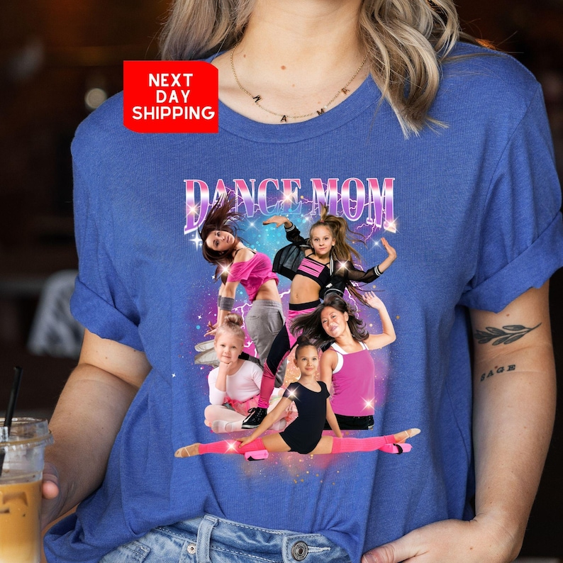 K&ouml;nnte beinhalten: Ein blaues T-Shirt mit dem Text "Dance Mom" in rosa und lila Buchstaben. Das Shirt zeigt eine Grafik mit f&uuml;nf M&auml;dchen in Tanzposen vor einem glitzernden Hintergrund.