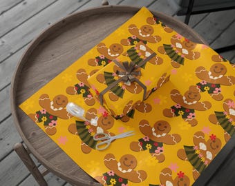 Puede incluir: Un regalo envuelto y papel de regalo con un patrón repetido de hombrecitos de jengibre con acentos florales sobre un fondo amarillo. También hay unas tijeras y un dispensador de cinta adhesiva transparente.