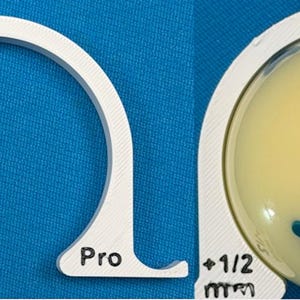 May include: Two-part image showing a white, semi-circular tool with the text "+1/2 mm" and "Pro". The second part shows a yellow sphere with three blue shapes. The background is a solid blue.