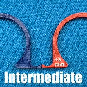 May include: Two arched, semi-circular tools, one blue and one orange, with measurements of +2 mm and +3 mm, respectively. The word "Intermediate" is printed in white below the tools. The tools are on a blue background.