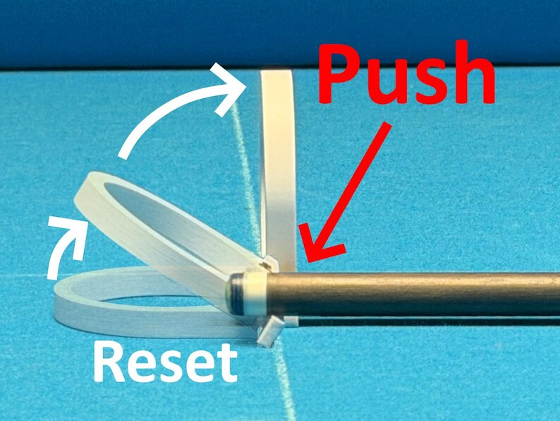 May include: Image showing a pool cue with a white and clear plastic device attached. The word "Push" is written in red, with a red arrow pointing towards the cue. The word "Reset" is written in white.