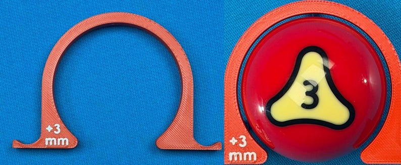 May include: An orange, semi-circular tool with "+3 mm" text, next to a red billiard ball with a yellow and black number "3" design. The tool appears to be a gauge or measuring device, possibly for pool or billiards.