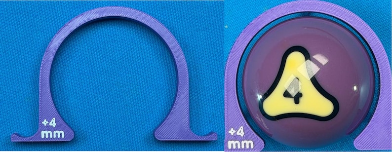 May include: A purple, semi-circular tool with a flat base and the text "+4 mm" printed in white. The tool is positioned next to a purple billiard ball with a yellow and black number four graphic.