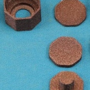 May include: A set of four brown, octagonal pieces. One piece is a hollow, open-topped octagon. Three additional pieces are solid octagons, one with a small, cylindrical post. The items are displayed on a blue surface.
