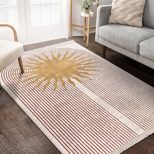 Puede incluir: Una alfombra de rayas blancas y rojas con un diseño de sol dorado en el centro. La alfombra tiene un borde de flecos.