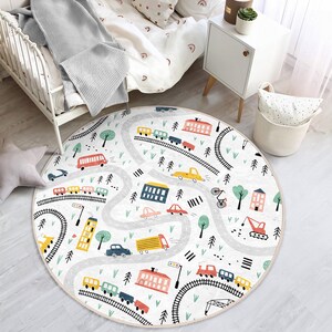 May include: A round, white play rug with a gray road design and colorful cars, trains, and buildings. The rug is perfect for a child's playroom or bedroom.