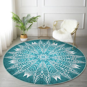 Puede incluir: Una alfombra redonda azul turquesa con un diseño de mandala blanco. La alfombra tiene un patrón detallado de hojas y espirales.