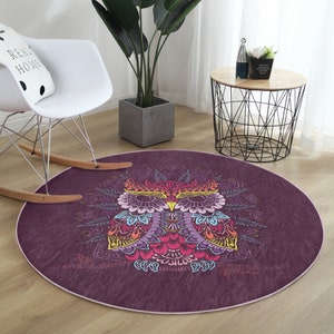 May include: A round, purple rug with a colorful owl design. The owl is surrounded by a mandala-like pattern with intricate details. The rug has a soft, plush texture.