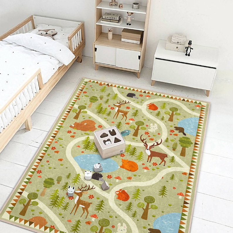 Puede incluir: Una alfombra de juego verde y marr&oacute;n con un camino sinuoso y varias ilustraciones de animales, incluyendo ciervos, zorros y ardillas. La alfombra es perfecta para la sala de juegos o el dormitorio de un ni&ntilde;o.