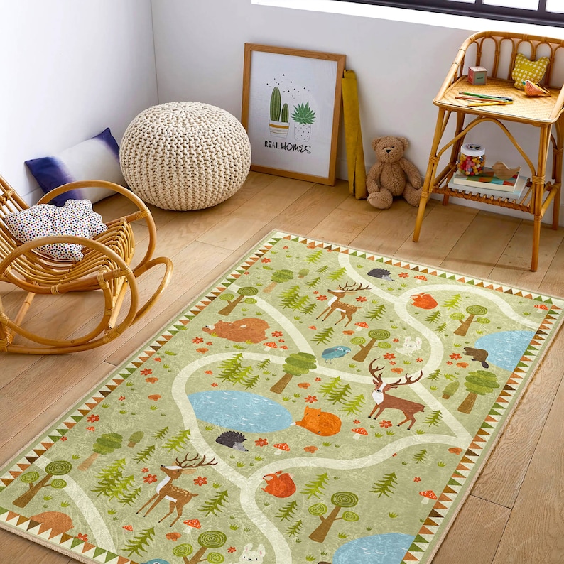 Puede incluir: Una alfombra de juego verde y marr&oacute;n con un camino sinuoso y varias criaturas del bosque, incluyendo ciervos, zorros y erizos. La alfombra tiene un fondo verde claro con acentos marrones y naranjas. El texto "Real Homes" es visible en el fondo.