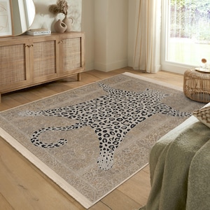 May include: A beige and cream area rug with a black and white leopard print design. The rug features a large leopard print design in the center, with a more intricate pattern around the edges.