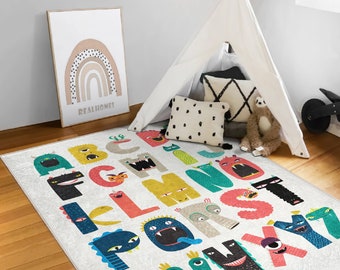May include: A white play rug with a colorful alphabet printed on it. Each letter is a monster with different colors, patterns, and expressions. The rug is on a wooden floor in a room with a teepee tent and a framed print of a rainbow.