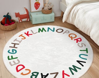 May include: A round, white play rug with a colorful alphabet border. The letters are in a circle around the edge of the rug.