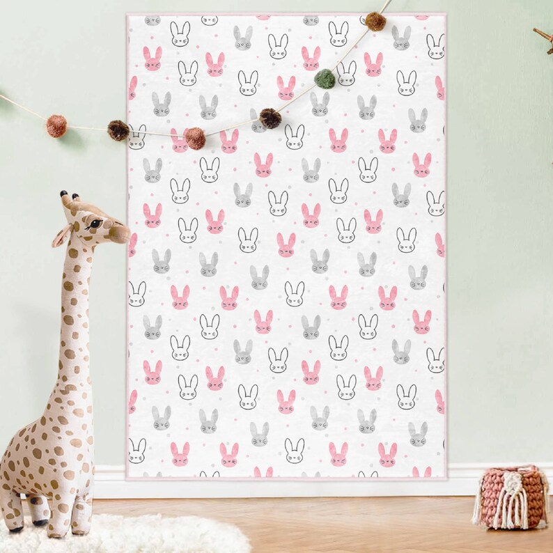 May include: A white background with a repeating pattern of pink and gray bunny faces. The bunnies have black eyes and whiskers. The background is dotted with small white dots.