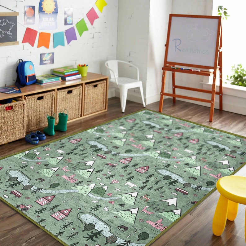 May include: A green and pink play rug with a woodland theme. The rug features mountains, trees, houses, and animals. The rug is perfect for a child's playroom or bedroom.