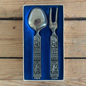 May include: A set of silver-plated cutlery in a blue box. The spoon and fork have intricate designs and are in a gift box.