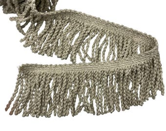 May include: A length of beige fringe trim with a woven top edge and long, twisted fringe. The trim is made of a thick, textured material and is suitable for various craft and sewing projects.