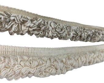 May include: Close-up of two decorative trims. The top trim features a textured, looped design in shades of gray and white. The bottom trim is a similar style, but in a solid off-white color. Both trims have a woven base.