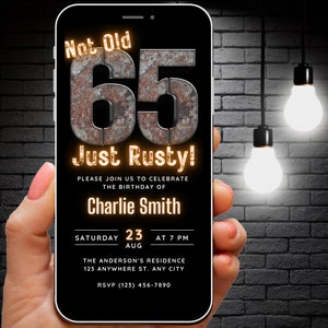 Könnte beinhalten: Ein schwarzes Smartphone mit einer Geburtstagseinladung auf dem Bildschirm. Die Einladung ist für eine 65. Geburtstagsfeier und lautet "Nicht alt, nur rostig!" Die Party findet am Samstag, den 23. August um 19:00 Uhr statt. Die Einladung ist für Charlie Smith und enthält die Adresse und RSVP-Informationen.