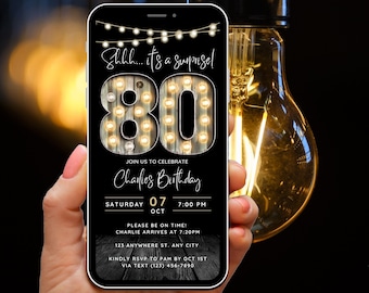 May include: A black smartphone with a birthday invitation on the screen. The invitation features a wooden sign with light bulbs spelling out "80" and the text "Shhh... it's a surprise!"  The invitation is for Charlie's 80th birthday party on Saturday, October 7th at 7:00 PM. The invitation includes the address and RSVP information.
