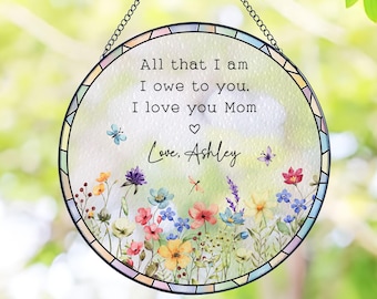 Może przedstawiać: Okrągły witraż z czarnym metalowym łańcuchem do zawieszenia. Panel przedstawia kwiatowy wzór i tekst "All that I am I owe to you. I love you Mom Love, Ashley."