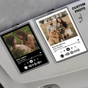 May include: Two car visor photo displays with custom photos. One displays a couple with the song "Better Together" by Jack Johnson. The other displays a family with the song "Grow Old with You" by Adam Sandler. Both have a music player interface.