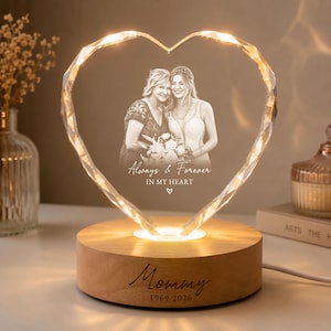 May include: A heart-shaped glass plaque with a laser-etched photograph of two people, the text "Always & Forever IN MY HEART", and a small heart icon. The plaque sits on a round wooden base engraved with "Mommy 1969-2026" and features internal lighting.