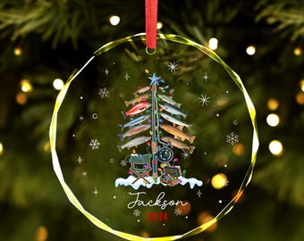 May include: A round glass Christmas bauble featuring a fishing-themed Christmas tree. The tree is adorned with colourful fish, a fishing rod, a tackle box, and a camping chair. The bauble is personalised with the name "Jackson" and the year "2024".