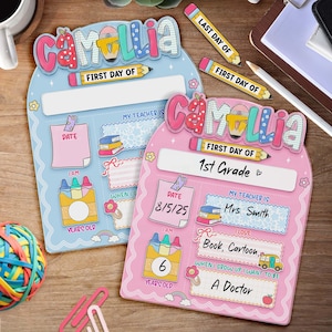 K&ouml;nnte beinhalten: Zwei farbenfrohe Schultafeln f&uuml;r den ersten Schultag, eine blaue und eine rosa, mit dem Namen "Camellia" oben. Die rosa Tafel zeigt "1st Grade" und enth&auml;lt das Datum "8/5/25". Beide Tafeln haben Platz f&uuml;r Informationen.