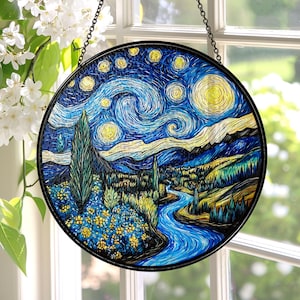 May include: Round stained glass art piece depicting Van Gogh's "Starry Night" with a black metal frame and hanging chain. The artwork features a swirling blue night sky with yellow stars, a river, and a village.