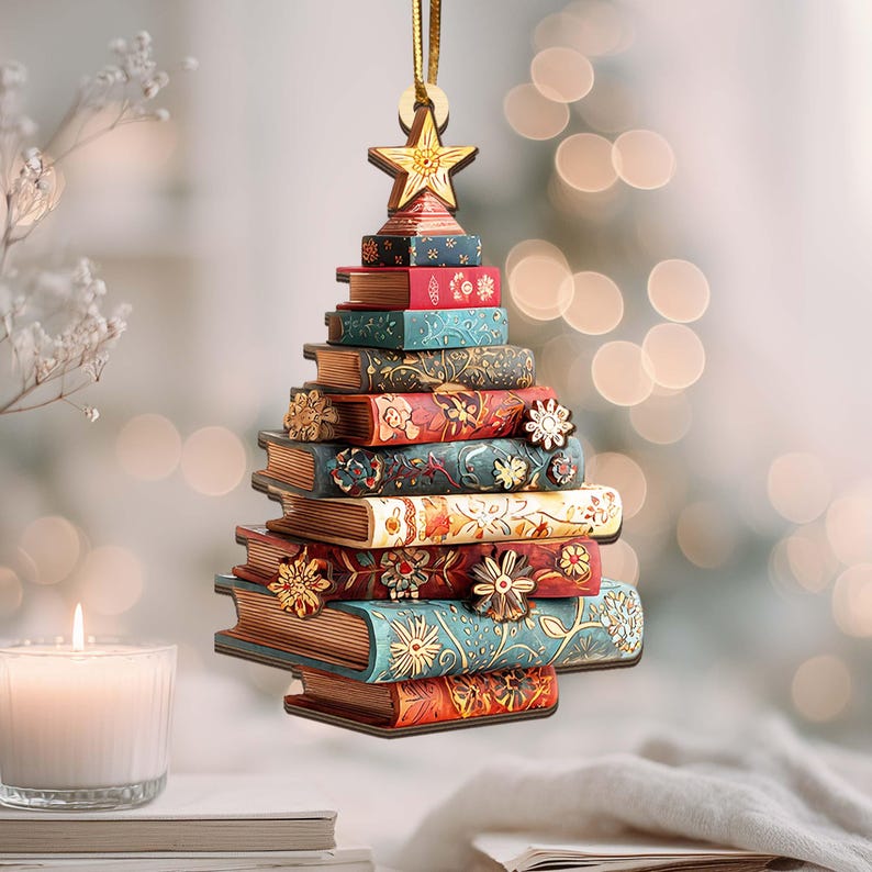 K&ouml;nnte beinhalten: Ein Weihnachtsbaumschmuck in Form eines Baumes aus gestapelten B&uuml;chern. Die B&uuml;cher sind in verschiedenen Farben gehalten, darunter Rot, Blau und Gold, und mit floralen Mustern verziert. Ein goldener Stern sitzt oben.