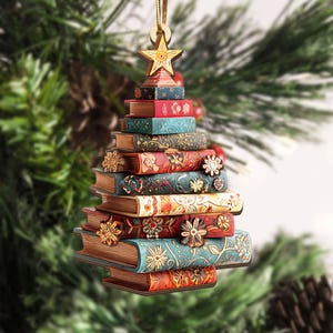 K&ouml;nnte beinhalten: Weihnachtsbaumschmuck in Form eines Baumes aus gestapelten B&uuml;chern. Die B&uuml;cher sind in Rot-, Blau- und Goldt&ouml;nen bemalt und mit floralen Mustern verziert. Ein goldener Stern sitzt oben, mit einer goldenen Schnur zum Aufh&auml;ngen.